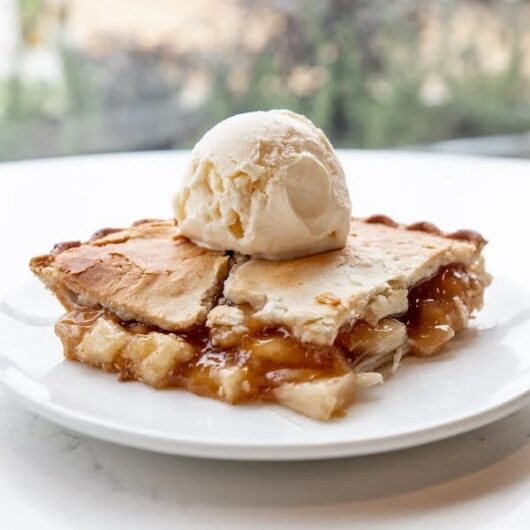 Delicious apple pie served with a scoop of vanilla ice cream on a plate