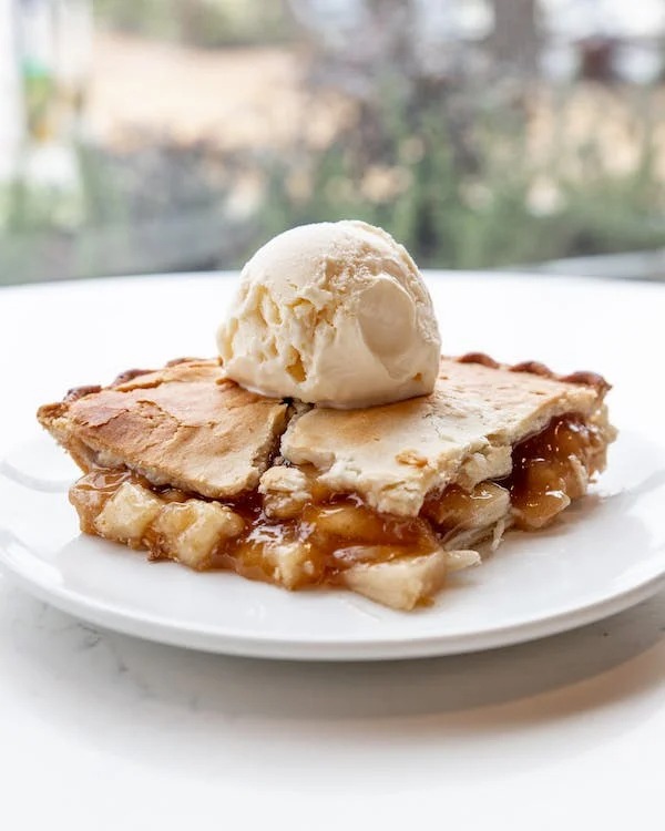 Delicious apple pie served with a scoop of vanilla ice cream on a plate