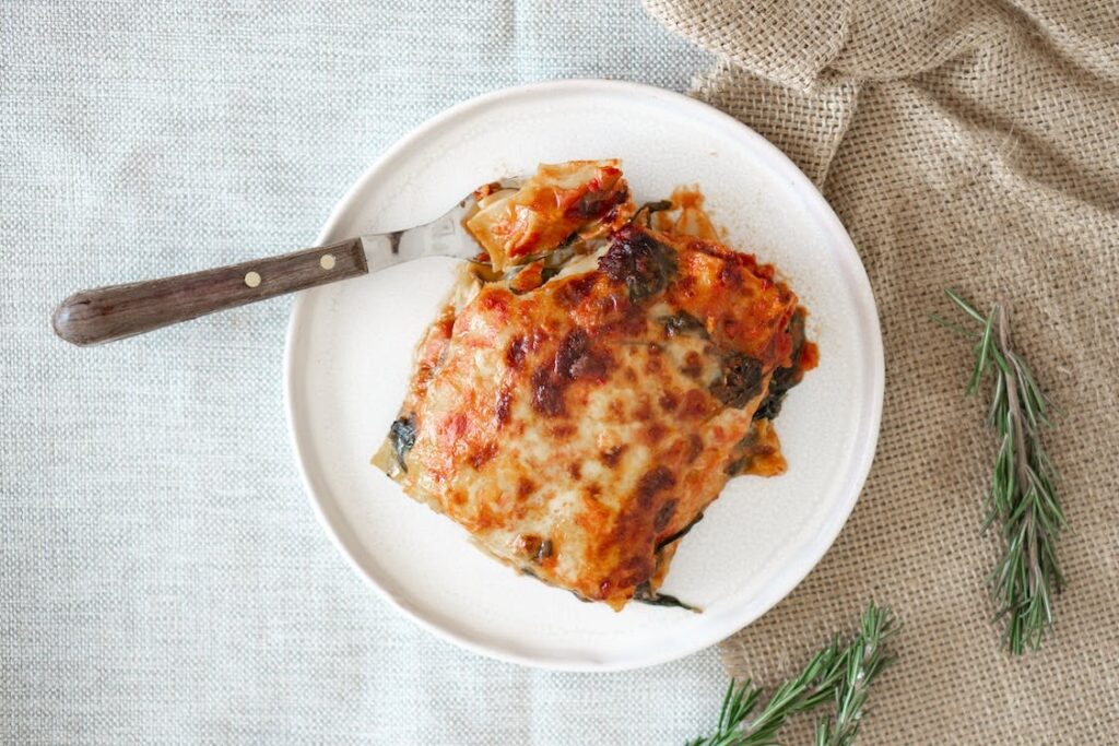 Delicious homemade beef lasagna on a white ceramic plate, garnished with fresh basil leaves.